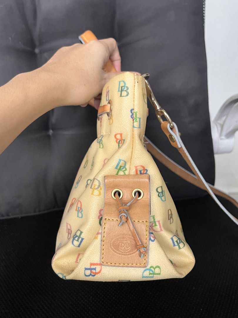 🇺🇸 Dooney & Bourke Multicolored DB Monogram Yellow Handbag (Category: Luxury Bags & Wallets) located in Manila. Submitted by prelovedpick.com (Listing ID 1469594492, Image 3). Description: With Freebies - Brand: Dooney & Bourke - Color: Cream with multicolored DB monogram print - Material: Coated canvas with tan leather trim - Straps: Top handles and a detachable shoulder strap - Hardware: Gold-tone with pink enamel heart charm - Details: Draws