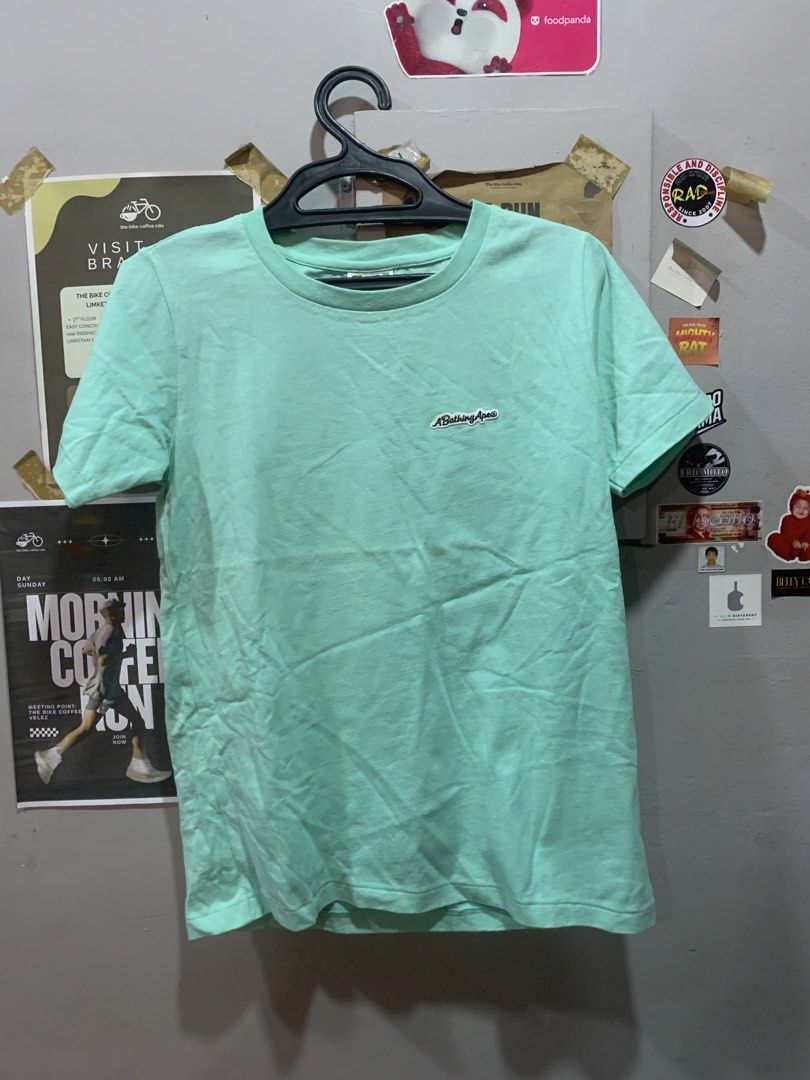 A Bathing Ape Green T-Shirt (Category: Shirts) located in Cagayan de Oro. Submitted by agboysalis60090 (Listing ID 1469711149, Image 1). Description: Mint green A Bathing Ape ladies t-shirt in size small. Small embroidered logo patch on the front chest. Large white ape head graphic printed across the back. 100 percent cotton material. Made in China. Nowhere Co., Ltd tag inside neck. Short sleeves, crew neck style..