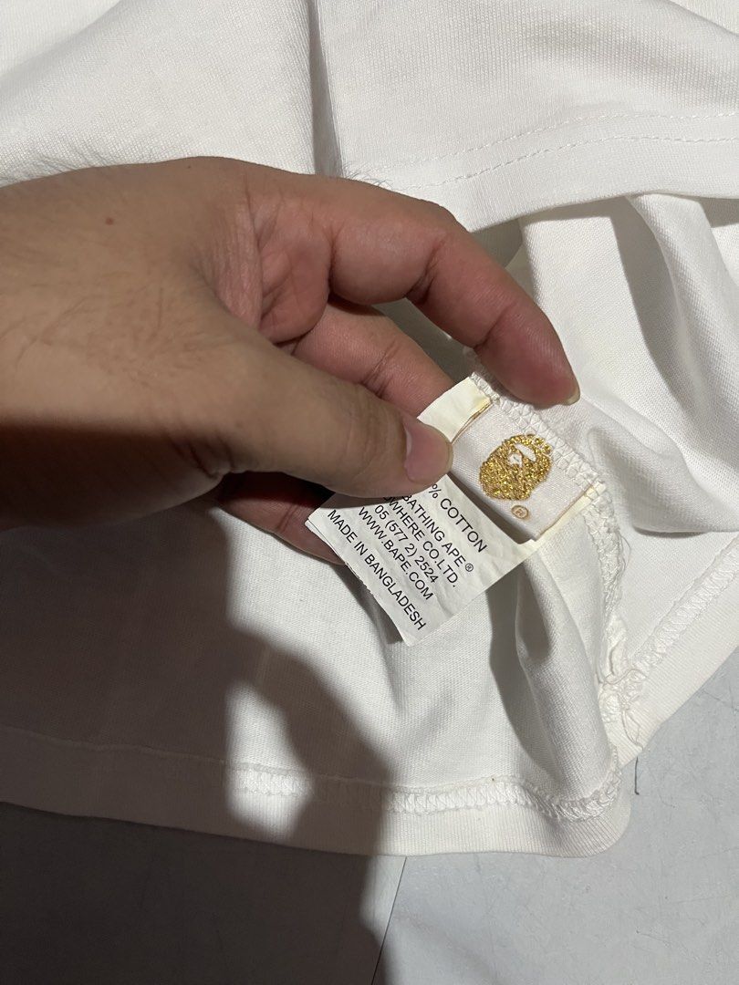 A Bathing Ape White Ape Logo T-Shirt (Category: Tshirts & Polo Shirts ) located in Cavite. Submitted by christianzuuu (Listing ID 1469740620, Image 2). Description: - Issues: 9/10 colorate need wash - Brand: Bape - Color: White with green and brown Ape head graphic - Size: Tagged 2XL (Actual measurements: 20" width x 27" length) - Material: 100% cotton, Made in Bangladesh - Condition: Includes original neck label and sleeve ape tag - Style: Class