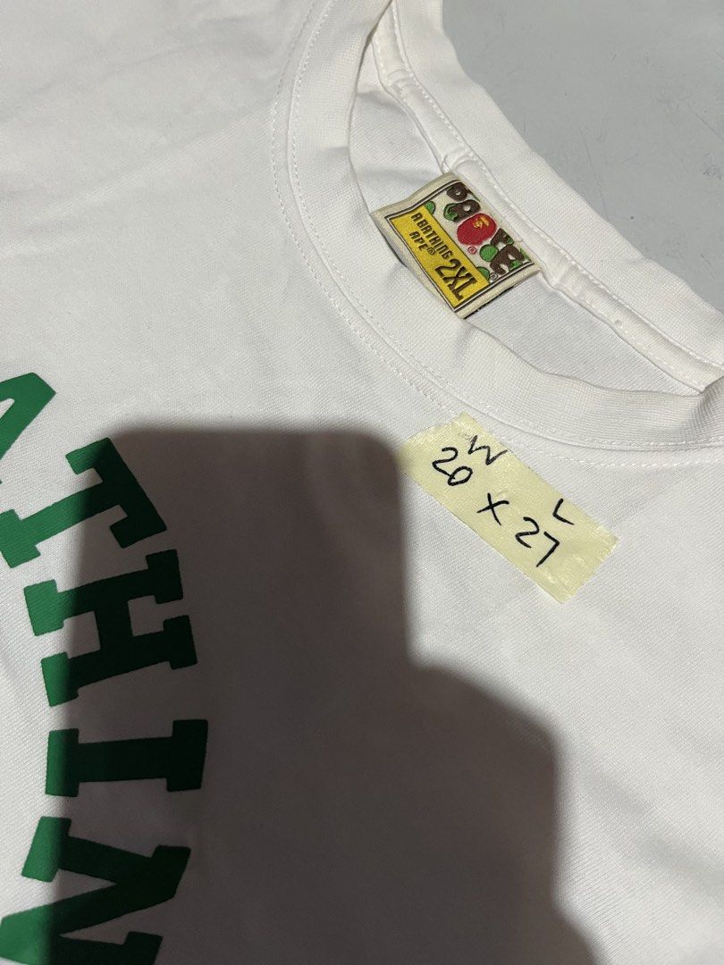 A Bathing Ape White Ape Logo T-Shirt (Category: Tshirts & Polo Shirts ) located in Cavite. Submitted by christianzuuu (Listing ID 1469740620, Image 3). Description: - Issues: 9/10 colorate need wash - Brand: Bape - Color: White with green and brown Ape head graphic - Size: Tagged 2XL (Actual measurements: 20" width x 27" length) - Material: 100% cotton, Made in Bangladesh - Condition: Includes original neck label and sleeve ape tag - Style: Class