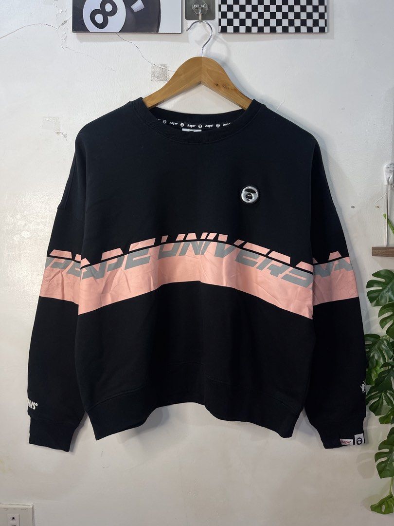 AAPE By A Bathing Ape Universe Black Sweatshirt (Category: Coats, Jackets and Outerwear) located in Cabagan. Submitted by blessingma81004 (Listing ID 1469738585, Image 2). Description: - Brand: AAPE - Color: Black with pink/silver graphic stripe - Size: Tagged XXS, but fits like a Medium (Measurements: Width 24" x Length 23") - Details: Metallic ape logo patch on left chest - Condition: Clean and ready to wear, minor print scratch on graphics.