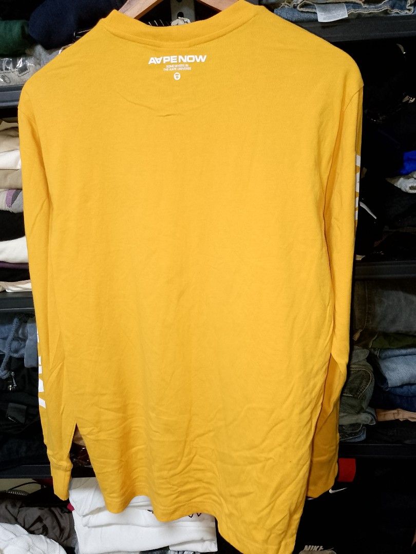 AAPE NOW Yellow Long Sleeve Tee (Category: Tshirts & Polo Shirts ) located in Manila. Submitted by mjthrifted_second (Listing ID 1469638798, Image 2). Description: - Brand: AAPE NOW - Item: Bright yellow long sleeve t-shirt - Size: Large (L) -Dimes: 20/27 - Condition: Brand new with tags attached, never worn - Details: Graphic text on sleeves and back collar, embroidered ape head logo on chest - Style: Clean, vibrant piece perfect for everyday st