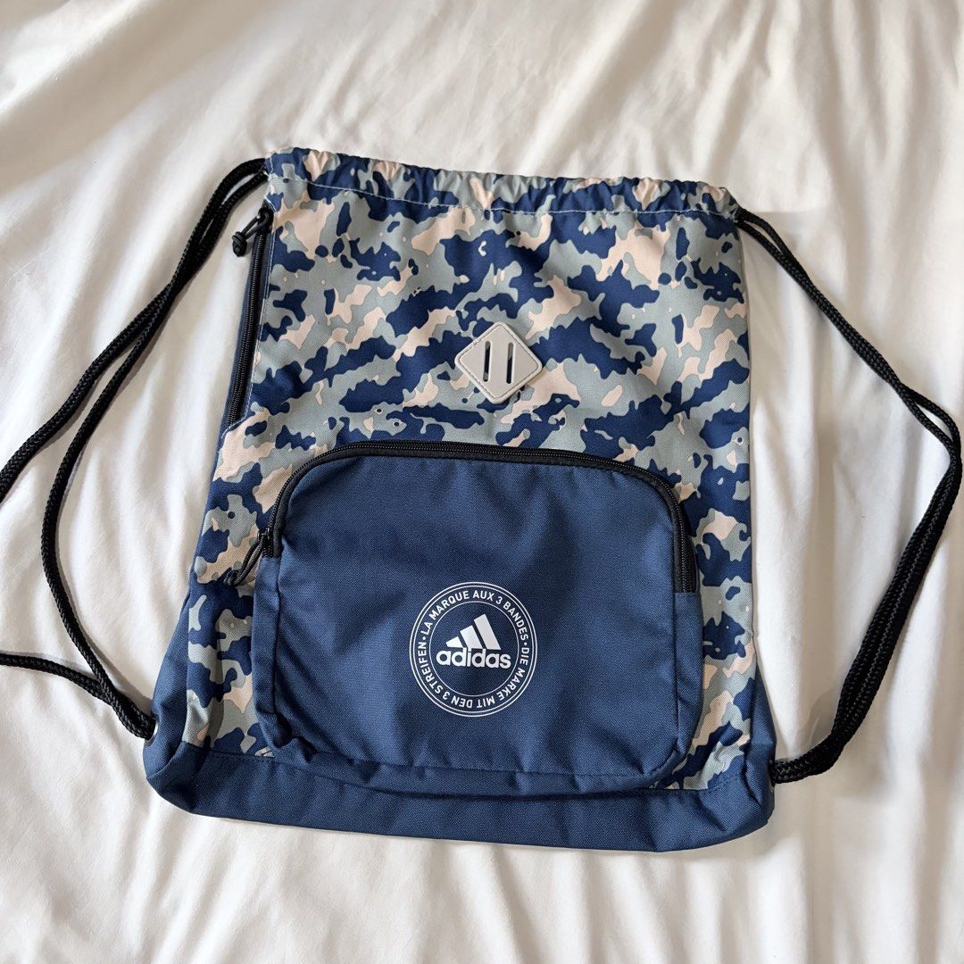 Adidas Camo Gym Sack Drawstring Bag Blue (Category: Backpacks) located in Quezon City. Submitted by angelajuliet__ (Listing ID 1469611533, Image 1). Description: - Brand: Adidas - Design: Blue camo pattern with classic circular logo print - Storage: Large main compartment with secure drawstring closure - Extra features: Front zippered pocket and grey diamond lash tab - Condition: Clean overall, perfect for the gym, school, or daily errands.
