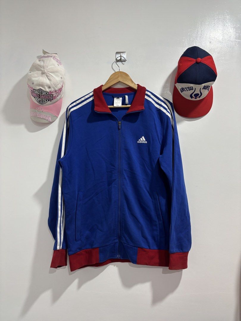 Adidas Climalite Full Zip Track Jacket Blue Red XL (Category: Coats, Jackets and Outerwear) located in Calbayog City. Submitted by zaxcheus_castillo1708 (Listing ID 1469667969, Image 1). Description: - Brand: Adidas - Style: Full-zip track jacket with stand-up collar and side pockets - Color: Blue body with red collar, cuffs, and hem, plus white accents - Details: White three-stripe sleeves and printed Adidas logo on the chest - Technology: Clima