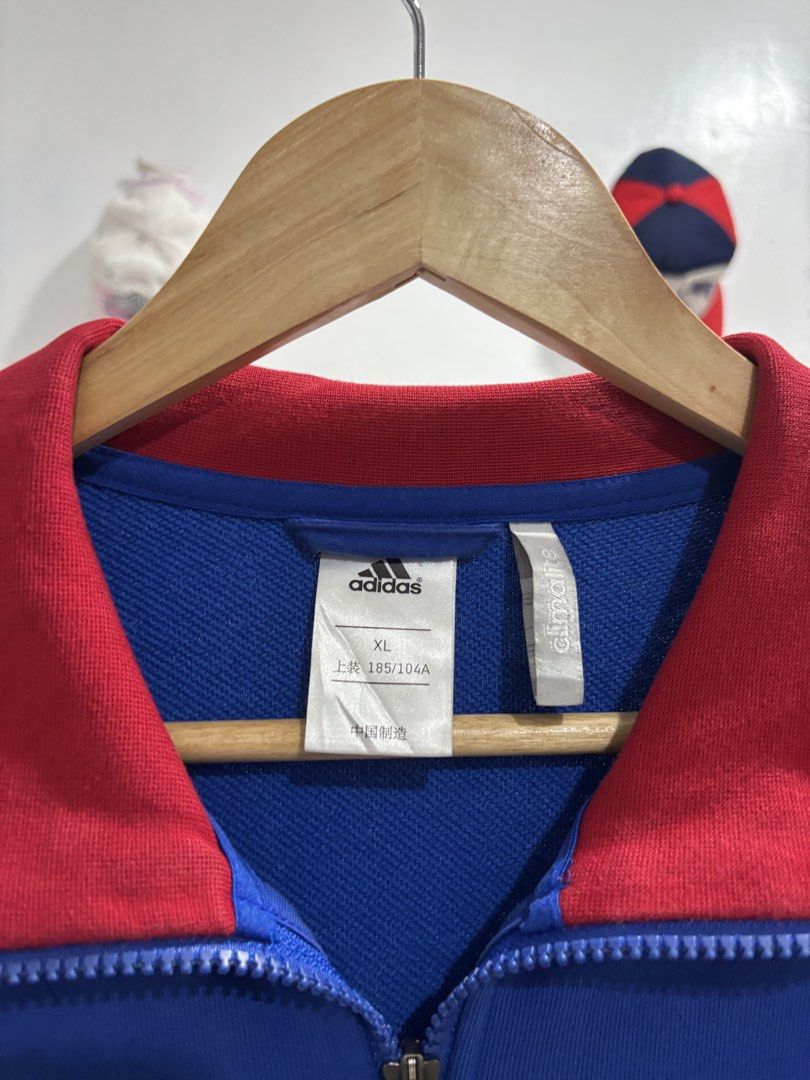Adidas Climalite Full Zip Track Jacket Blue Red XL (Category: Coats, Jackets and Outerwear) located in Calbayog City. Submitted by zaxcheus_castillo1708 (Listing ID 1469667969, Image 2). Description: - Brand: Adidas - Style: Full-zip track jacket with stand-up collar and side pockets - Color: Blue body with red collar, cuffs, and hem, plus white accents - Details: White three-stripe sleeves and printed Adidas logo on the chest - Technology: Clima