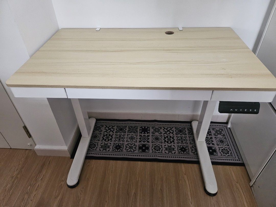 Adjustable study table (Category: Tables & Sets) located in Singapore. Submitted by shopwithmebabes (Listing ID 1469629904, Image 1). Description: - Adjustable standing/study table with smooth electronic height control - Light wood-grain tabletop with a clean white sturdy metal frame - Built-in digital control panel with memory height presets - Convenient cable management grommet hole on the desktop .