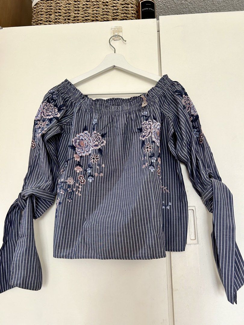 American Eagle Striped Embroidered Off-The-Shoulder Blouse (Category: Blouses) located in Manila. Submitted by isabelle_1104 (Listing ID 1469644992, Image 1). Description: Blue and white striped off-the-shoulder top from American Eagle Outfitters. Size XS. Pretty floral embroidery details scattered on the front and sleeves. Long sleeves with tie cuffs. Elastic neckline. Lightweight material, great for warm weather. Clean and well maintained..