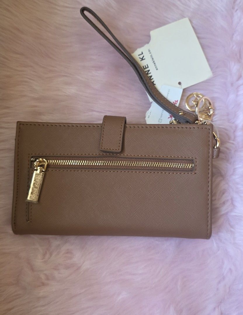 Anne Klein Brown Wristlet Wallet with Tags (Category: Wallets & Card holders) located in Amadeo. Submitted by riccchfinds (Listing ID 1469649905, Image 2). Description: - Brand: Anne Klein - Color: Brown - Material: Textured Saffiano finish with gold-tone hardware - Features: Detachable wrist strap, exterior zip pocket, multiple card slots, and ID window - Closure: Secure snap button - Condition: Brand new with original store tags attached.