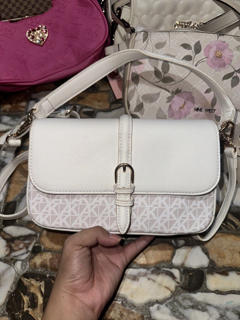 Anne Klein White Crossbody Bag with Monogram Pattern (Category: Cross-body Bags) located in Bugallon. Submitted by lavenderlane (Listing ID 1469669272, Image 2). Description: - Brand: Anne Klein - Color: White and beige with gold-toned hardware - Design: Monogram print on the lower front with flap top and buckle accent - Strap: Adjustable shoulder strap - Interior: Fabric lined with a zippered pocket and brand patch - Condition: Brand new with or