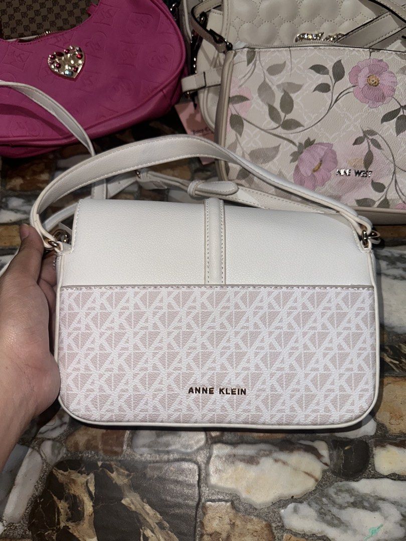 Anne Klein White Crossbody Bag with Monogram Pattern (Category: Cross-body Bags) located in Bugallon. Submitted by lavenderlane (Listing ID 1469669272, Image 1). Description: - Brand: Anne Klein - Color: White and beige with gold-toned hardware - Design: Monogram print on the lower front with flap top and buckle accent - Strap: Adjustable shoulder strap - Interior: Fabric lined with a zippered pocket and brand patch - Condition: Brand new with or