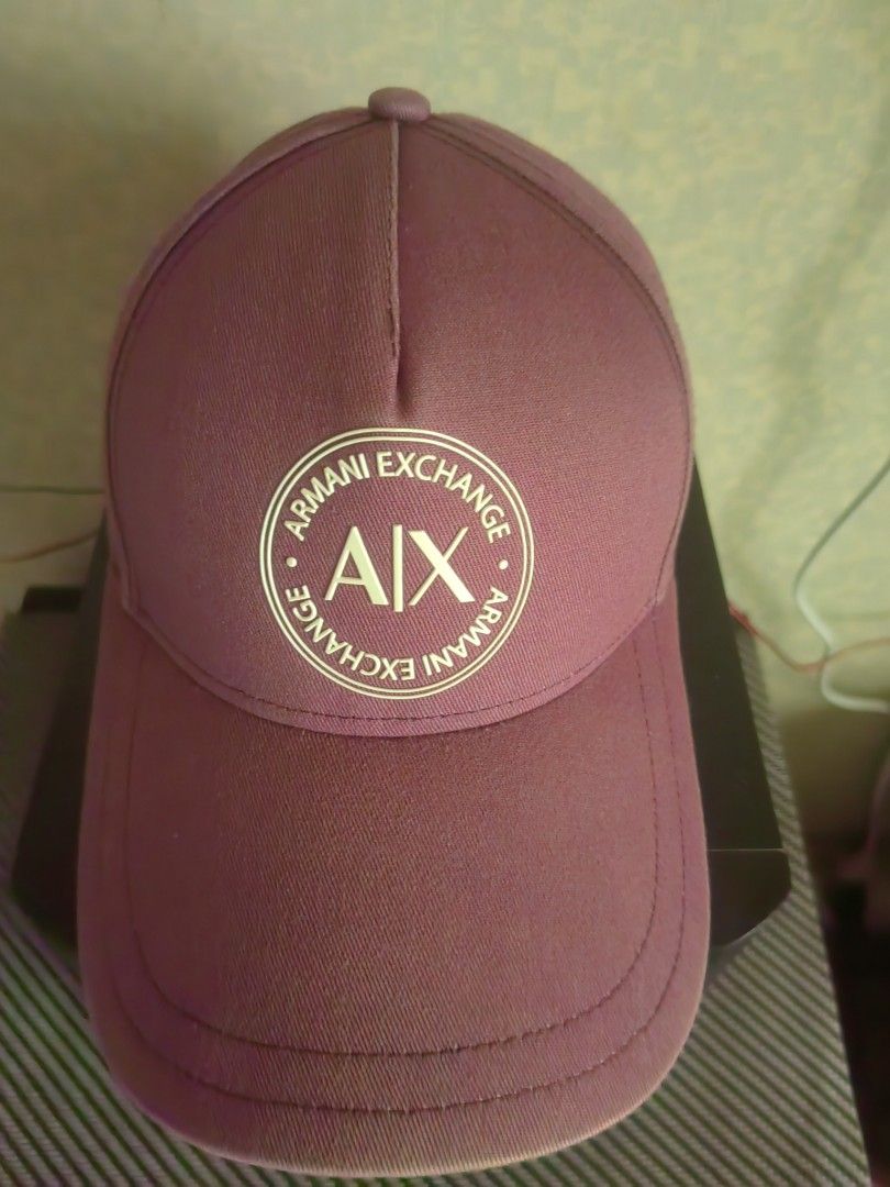 Armani Exchange Burgundy Baseball Cap (Category: Caps & Hats) located in Makati City. Submitted by donald1983 (Listing ID 1469579600, Image 1). Description: - Brand: Armani Exchange - Color: Burgundy with gold-tone hardware - Design: Circular AX logo patch on the front - Material: 100% cotton - Size: Universal (UNI), adjustable snapback closure - Details: Signature orange lettering taping along the inner seams .