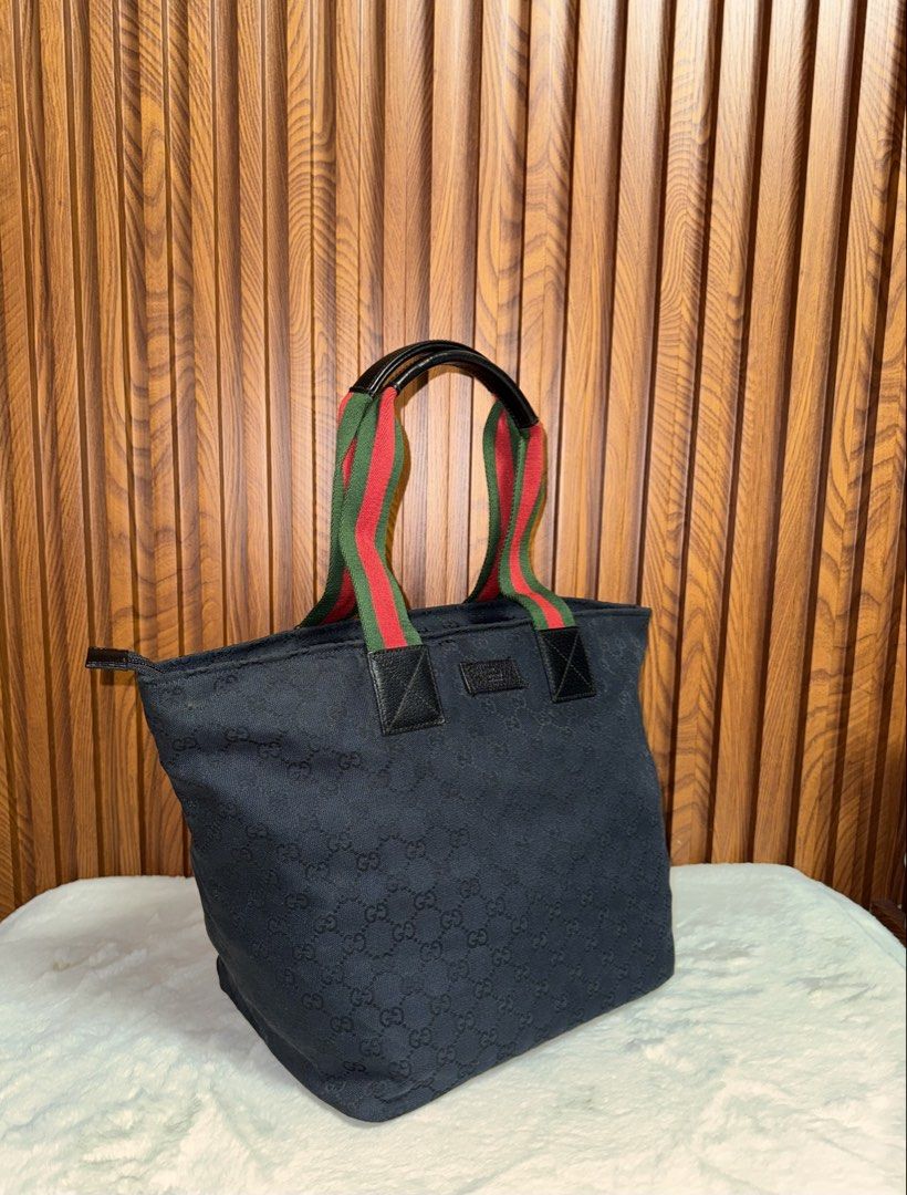 Authentic Gucci Monogram Canvas Tote Bag Black (Category: Everything Else Others) located in Subic. Submitted by luxshoppe88 (Listing ID 1469700627, Image 2). Description: Black canvas tote bag with iconic GG monogram pattern all over. Web stripe handles in red and green with black leather trim. Secure top zip closure and sturdy leather bottom base. Interior lined in black fabric with an extra slip pocket. Spacious design holds all daily essentia