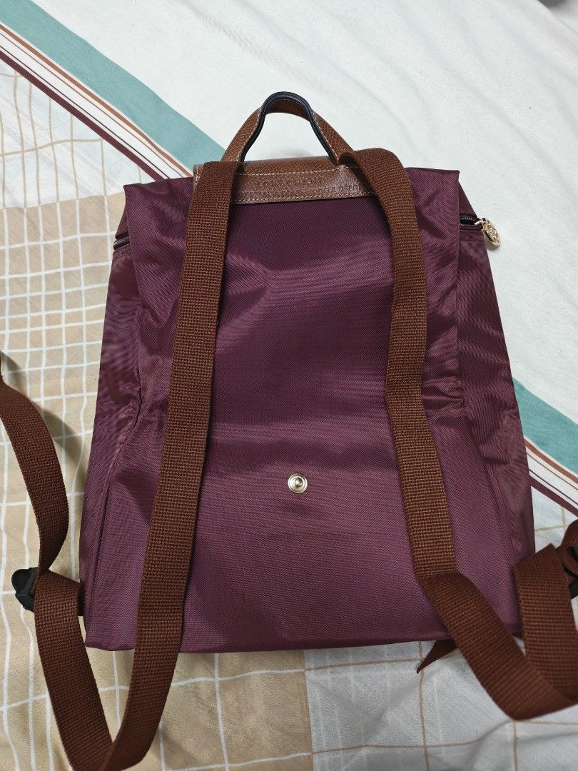 Authentic Longchamp Le Pliage Sac A Dos Backpack Plum (Category: Backpacks) located in Pasig City. Submitted by she_declutters_ph (Listing ID 1469645268, Image 3). Description: - Brand: Longchamp Le Pliage Backpack - Color: Plum with signature brown leather flap and top handle - Material: Durable nylon body with adjustable webbed shoulder straps - Design: Folds down into a compact size for easy storage - Closure: Front flap with snap button - Use