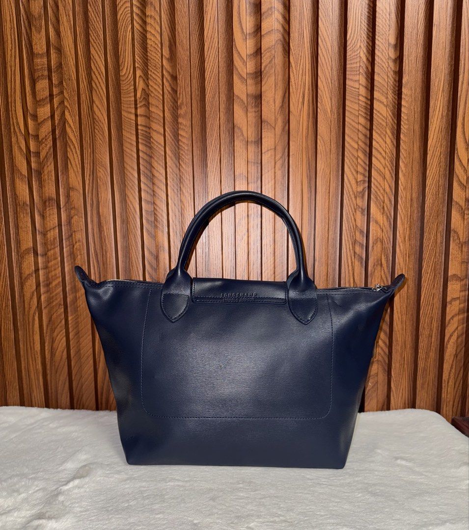 Authentic Longchamp Navy Blue Leather Tote Bag (Category: Everything Else Others) located in Subic. Submitted by luxshoppe88 (Listing ID 1469705366, Image 3). Description: - Brand: Longchamp - Color: Navy blue - Material: Smooth grain leather - Closure: Snap button flap with embossed horse logo - Handles: Double top handles - Base: Structured rectangular base - Interior: Spacious compartment for daily essentials - Condition: Clean corners and wel