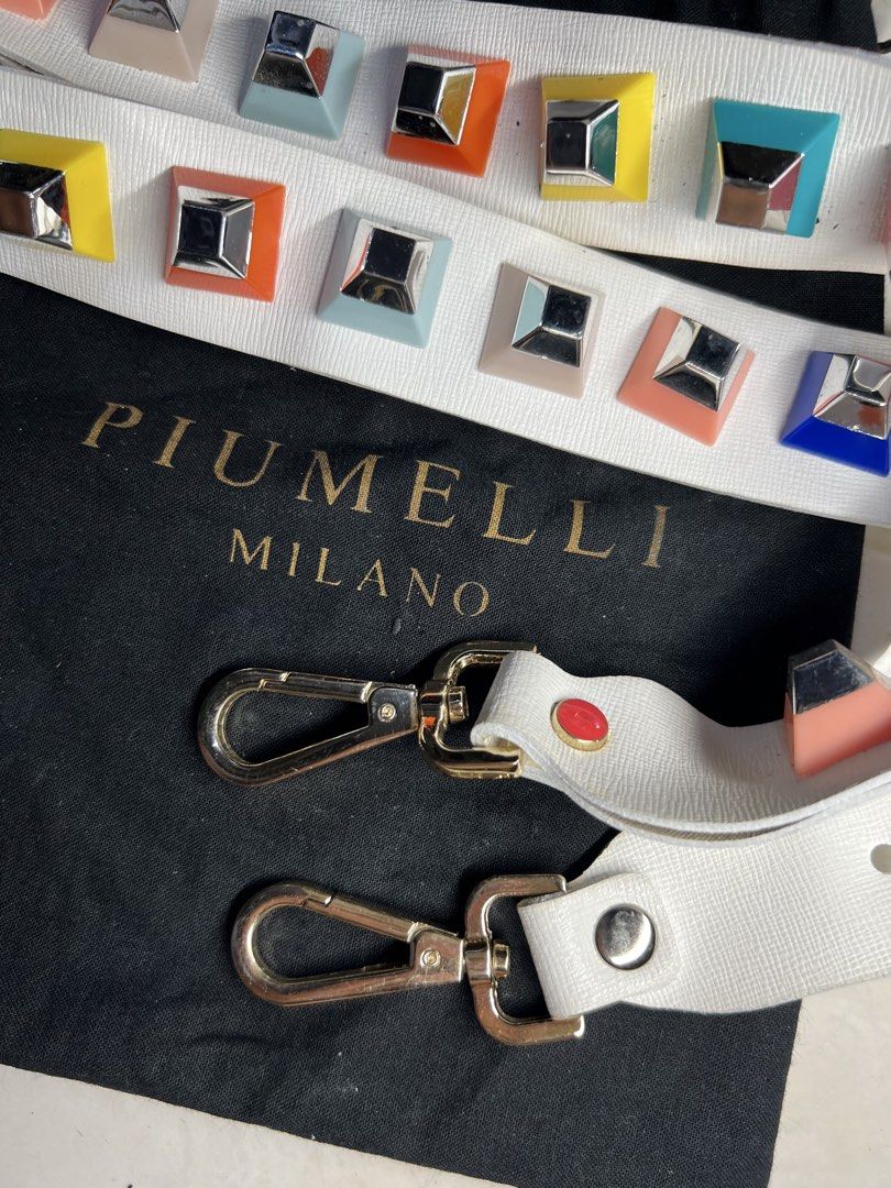 AUTHENTIC PIUMELLI Milano multi-color block studded decorative bag strap (Category: Luxury Bags & Wallets) located in General Santos City (Dadiangas). Submitted by queenfinds (Listing ID 1469720936, Image 3). Description: Piumelli Milano multi-color block studded decorative bag strap, displayed alongside its original gold-stamped black flannel dust bag. This piece features a premium white leather body adorned with two parallel rows of vibrant, mu