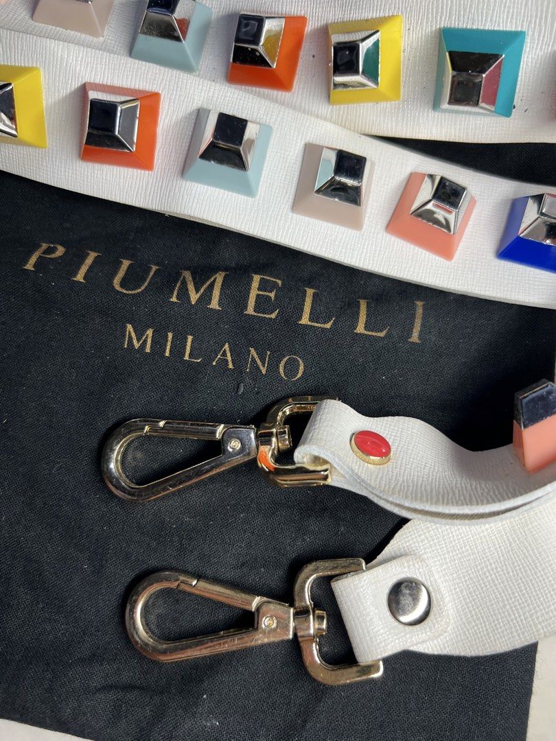 AUTHENTIC PIUMELLI Milano multi-color block studded decorative bag strap (Category: Luxury Bags & Wallets) located in General Santos City (Dadiangas). Submitted by queenfinds (Listing ID 1469720936, Image 1). Description: Piumelli Milano multi-color block studded decorative bag strap, displayed alongside its original gold-stamped black flannel dust bag. This piece features a premium white leather body adorned with two parallel rows of vibrant, mu