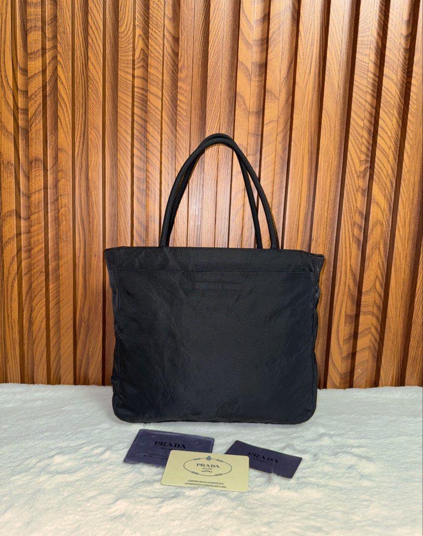 Authentic Prada Black Nylon Tote Bag (Category: Everything Else Others) located in Subic. Submitted by luxshoppe88 (Listing ID 1469699564, Image 1). Description: Classic black nylon tote bag from Prada. Double top handles, zip closure across the top. Interior lined with Prada logo fabric and metal plaque. Includes authenticity cards and tag. Clean condition overall, lightweight and practical for daily use. mode of payment : bpi and gcash shipping