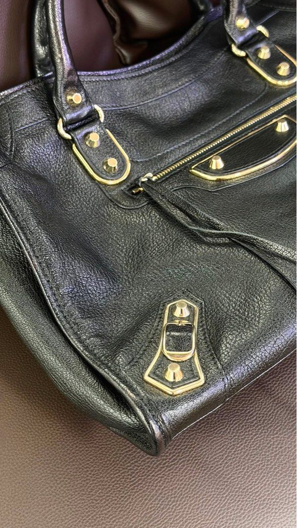 Balenciaga City Metallic Edge Medium (Category: Luxury Bags & Wallets) located in Pasig City. Submitted by the90sph (Listing ID 1469591685, Image 3). Description: Balenciaga City Medium Classic Motorcycle Tote in Metallic Edge Black leather with Gold hardware Inclusion: Bag, short strap, mirror, B101revue authenticity card Condition: very good, looks new tbh. no issues, even the leather, stitching, the piping and handles are very good Price: 70k 
