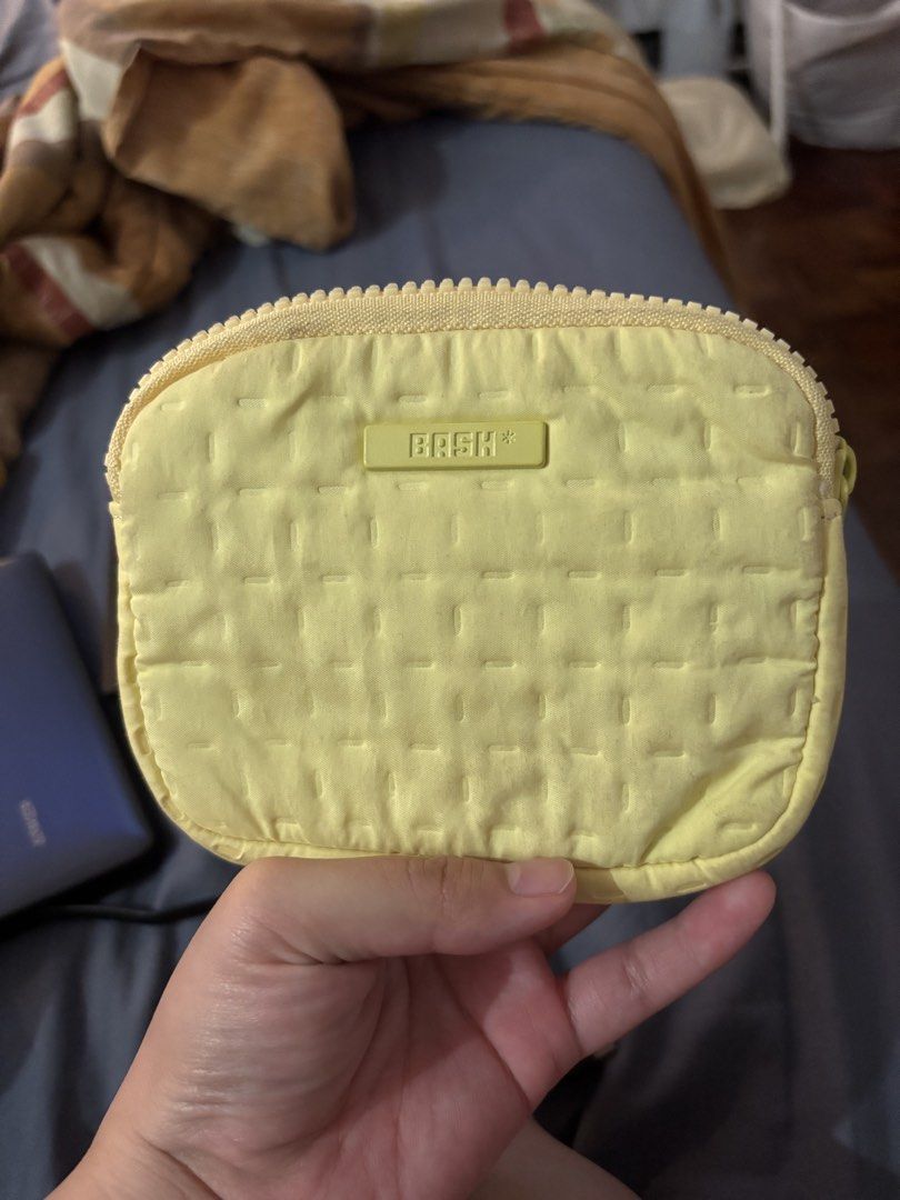 BASH Yellow Quilted Pouch (Category: Purses & Pouches) located in Quezon City. Submitted by ulan-declutter (Listing ID 1469655539, Image 1). Description: - Brand: BASH - Color: Bright yellow - Material: Soft quilted fabric with matching zipper - Design: Rectangular rubber patch logo on the front - Usage: Compact size, ideal for storing small essentials inside a larger bag.