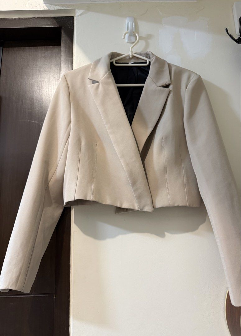 Beige cropped blazer jacket with black inner lining (Category: Coats, Jackets and Outerwear) located in Taguig. Submitted by decluttering_tita2 (Listing ID 1469700368, Image 1). Description: - Color: Cream / Beige with contrasting black inner lining - Style: Cropped blazer jacket with sharp lapels and structured long sleeves - Details: Clean front closure and vertical dart details for a tailored fit - Versatility: Great layering piece for both sm