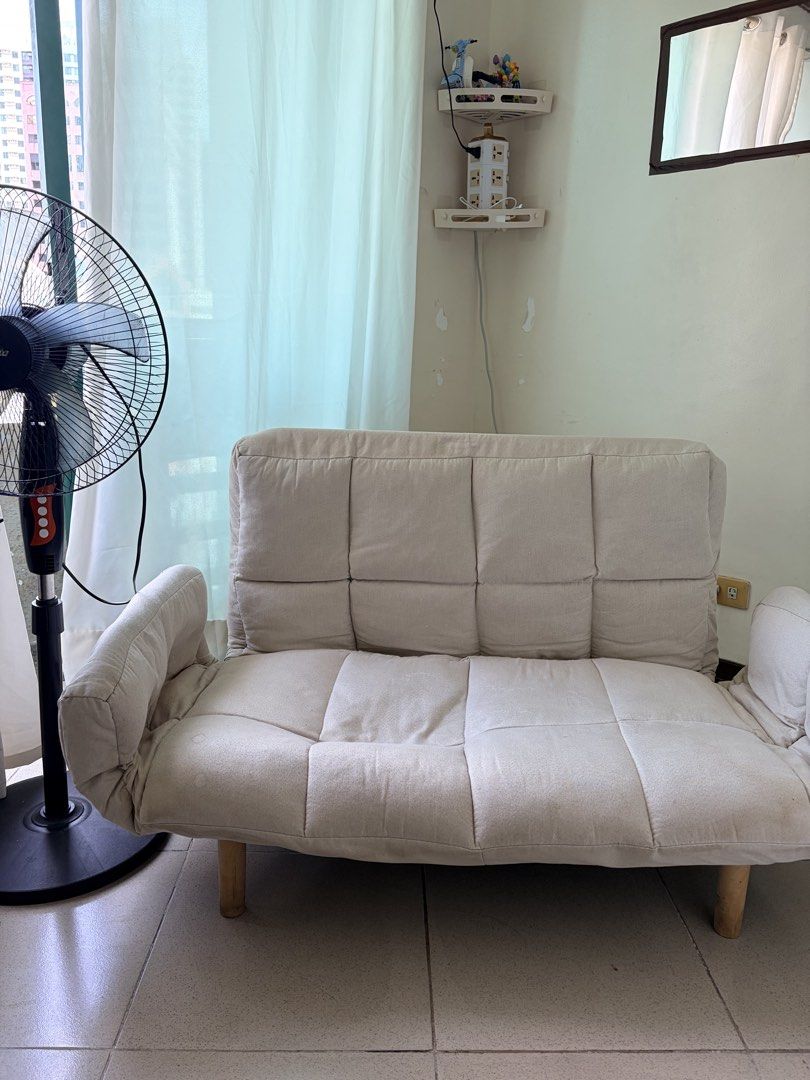 Beige foldable sofa bed with wooden legs (Category: Sofas) located in Makati City. Submitted by makatigirlpreloved (Listing ID 1469618608, Image 3). Description: - Beige tufted fabric sofa bed, adjustable backrest folds down completely flat. - discoloration and stains visible on the fabric surface, plus light scuff marks on the wooden legs. - selling with throw pillow .