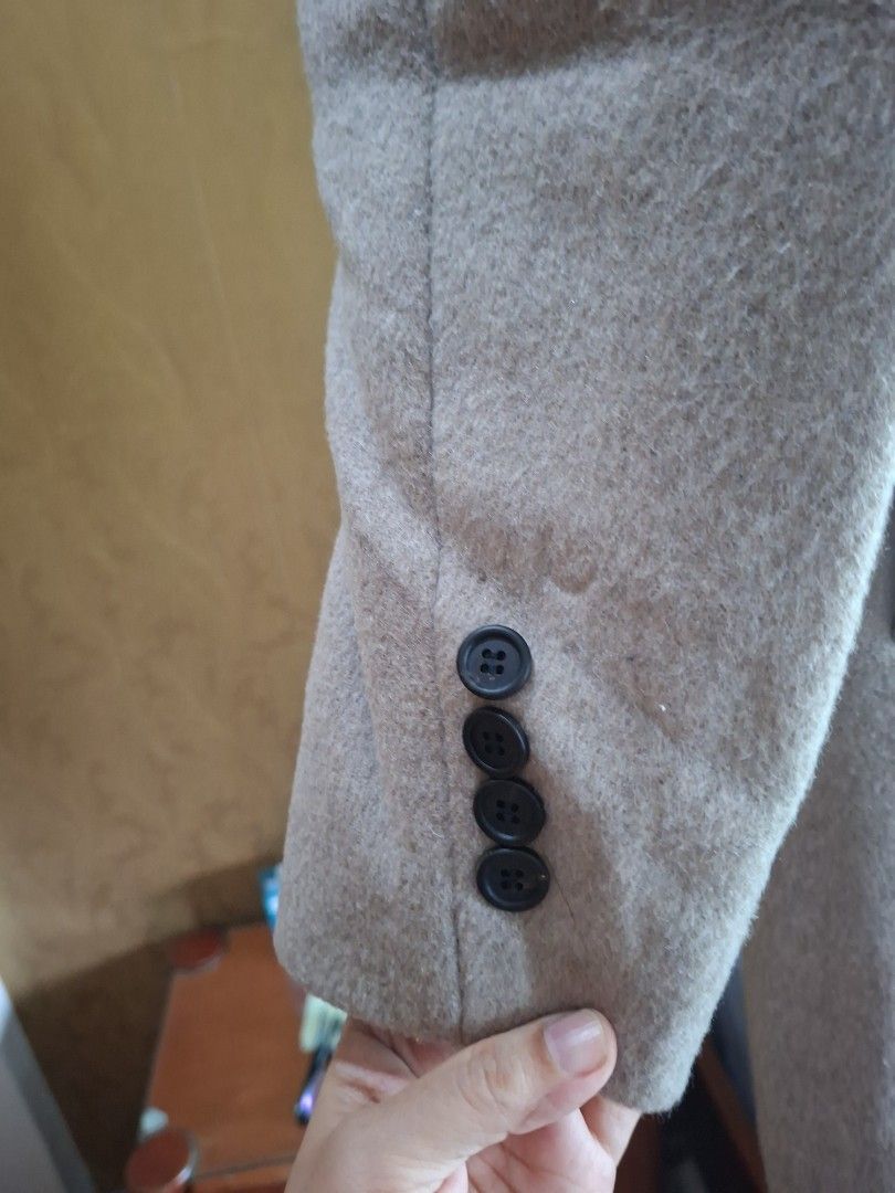Beige woolen trench coat winter outerwear (Category: Coats, Jackets and Outerwear) located in Quezon City. Submitted by apple.ana888 (Listing ID 1469628463, Image 2). Description: - Color: Elegant beige - Material: Warm wool-blend, fully lined interior - Style: Double-breasted front with two dark buttons and classic lapel collar - Length: Medium - Features: Two functional front pockets - Condition: Great for cold weather layering.