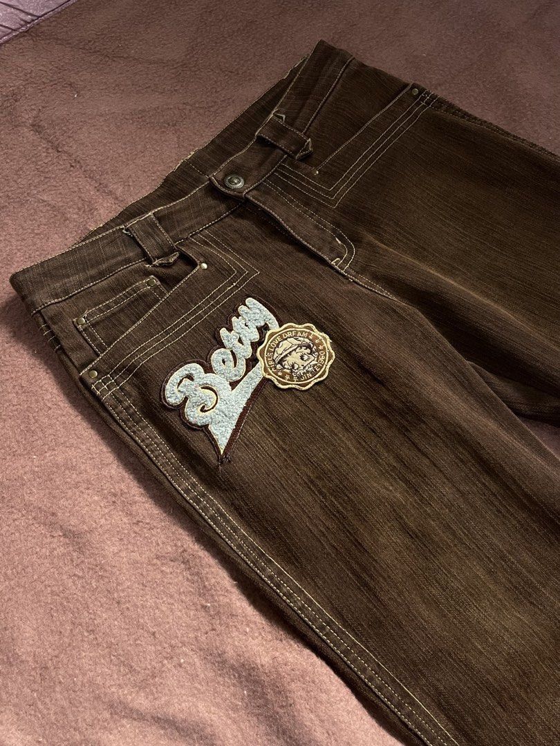 Betty Brown Denim Jeans Flared Pants with Patch (Category: Jeans) located in Mandaluyong City. Submitted by chienneclassique (Listing ID 1469689543, Image 2). Description: - Style: Vintage Y2K flared denim trousers - Color: Brown with light contrasting topstitching - Fit: Mid-rise waistband with belt loops and front button closure - Details: Large blue fuzzy 'Betty' embroidered patch and circular badge on the right front leg - Condition: Excellen