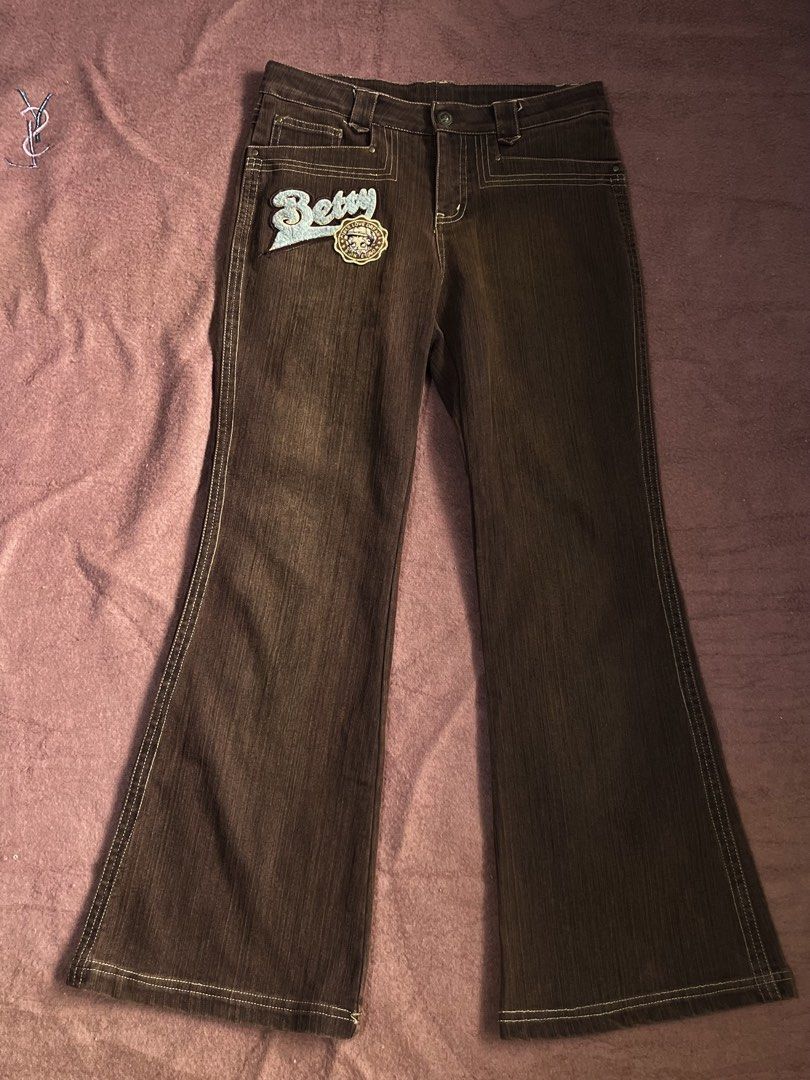 Betty Brown Denim Jeans Flared Pants with Patch (Category: Jeans) located in Mandaluyong City. Submitted by chienneclassique (Listing ID 1469689543, Image 1). Description: - Style: Vintage Y2K flared denim trousers - Color: Brown with light contrasting topstitching - Fit: Mid-rise waistband with belt loops and front button closure - Details: Large blue fuzzy 'Betty' embroidered patch and circular badge on the right front leg - Condition: Excellen