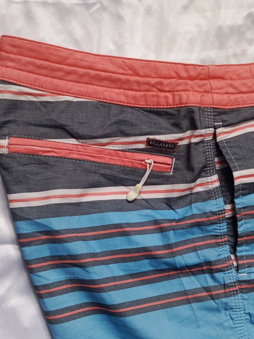 Billabong Striped Board Shorts Size 30 (Category: Swim Trunks & Board Shorts) located in City of Isabela. Submitted by warmbird.d06e6f (Listing ID 1469584182, Image 2). Description: - Brand: Billabong - Size: 30 - Design: Multi-color horizontal stripes (red, navy blue, light blue, and white) - Waistband: Coral pink with drawstring closure and metal eyelets - Pocket: Back zippered pocket with pull tab and branded woven label - Material: 51% cotton