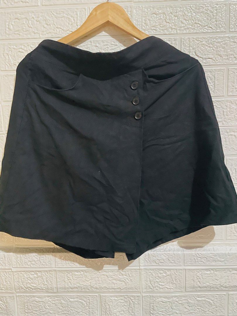 Black asymmetrical wrap skirt with button details (Category: Skirts) located in Manila. Submitted by myshanshine (Listing ID 1469576935, Image 1). Description: - Color: Black - Style: Flared cut with an asymmetrical wrap front - Details: Three decorative dark buttons on the side seam - Features: Two deep, functional side pockets near the waistband - Fabric: Smooth and comfortable finish - Versatility: Easy to match with any casual top.