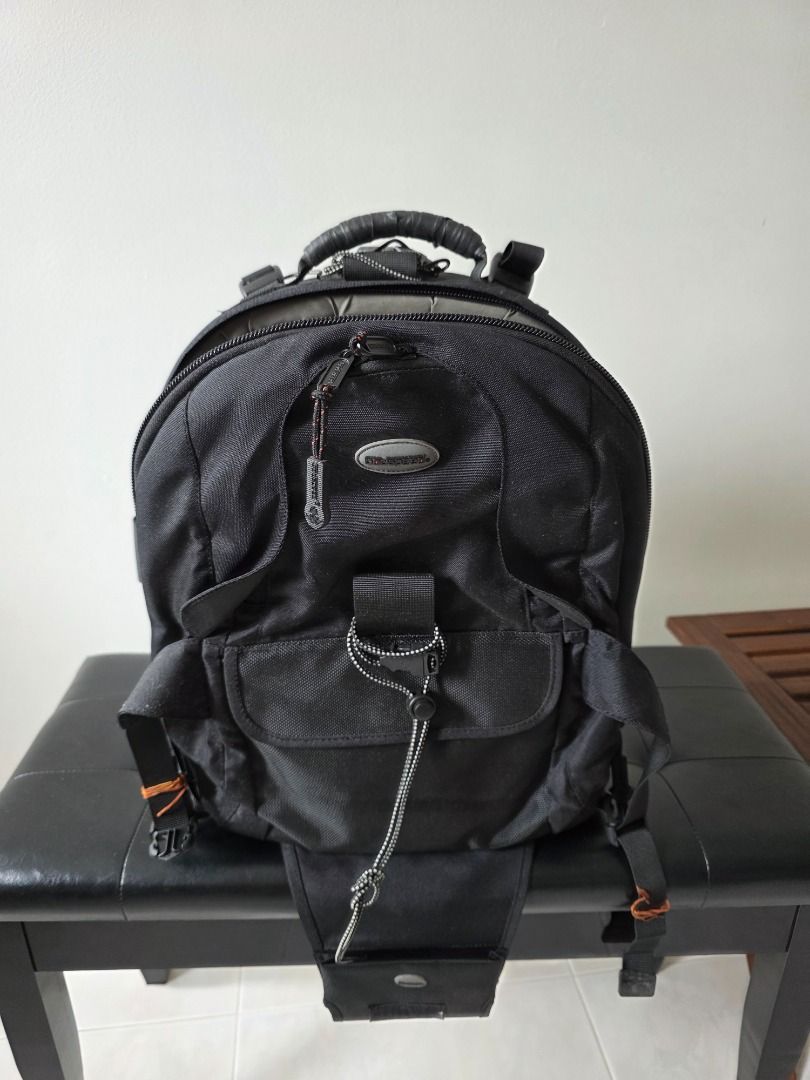 Black Camera Backpack (Category: Camera Bags & Carriers) located in Singapore. Submitted by andlpc2012 (Listing ID 1469701949, Image 1). Description: - Color: Black - Fully adjustable interior padded dividers for bodies and lenses - Multiple exterior pockets and secure bungee strap system - Sturdy top handle and side straps - Clean interior lining with mesh zippered pockets on the flap - Ideal practical gear bag for photographers can hold tripod,