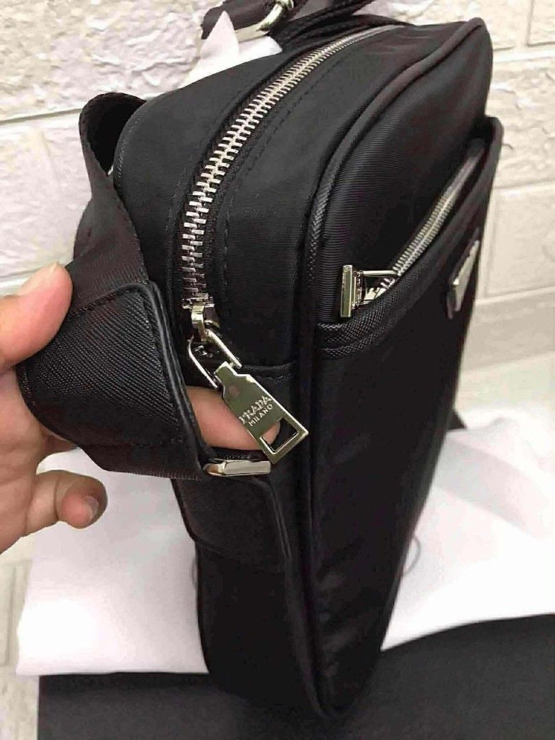 Black Nylon Crossbody Bag with Pouch (Category: Luxury Bags & Wallets) located in Manila. Submitted by prime.dlor (Listing ID 1469743033, Image 2). Description: Black nylon crossbody bag from Prada. Includes a matching mini pouch attached to the wide strap. Front zipper pocket with the enamel triangle logo plaque. Main compartment has a zip closure and signature jacquard lining. Silver-tone hardware throughout. Original box, dust bag, and green a