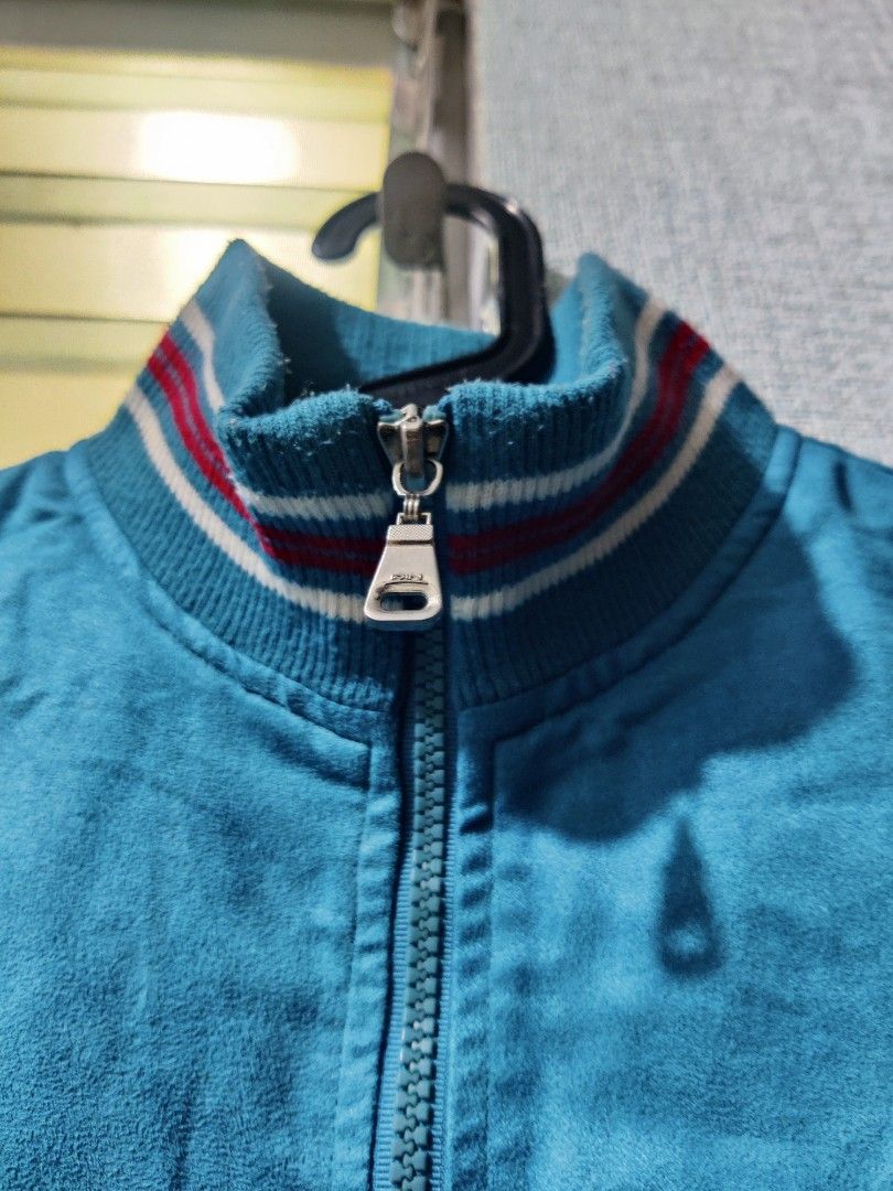 Retro Blue Jacket (Category: Coats, Jackets and Outerwear) located in Pasig City. Submitted by shiyenaaa (Listing ID 1469669183, Image 3). Description: - Color: Bright blue with red and white striped ribbed collar, cuffs, and hem - Material: Soft and comfortable fabric texture - Closure: Full front zipper with a metallic pull tab - Pockets: Two front slash pockets - Details: Small red tag near the right pocket - Style: Casual vintage vibe, great 