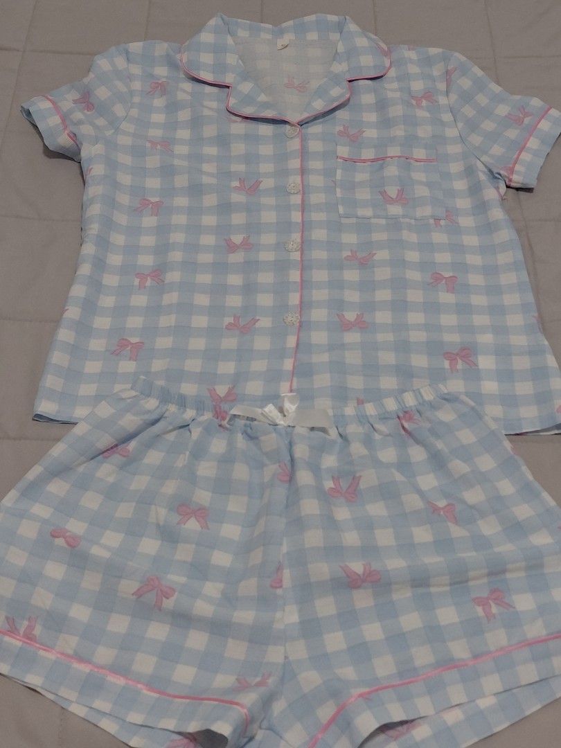 Blue Gingham Bow Pyjamas Set Short Sleeve Shorts (Category: Sets or Coordinates) located in Taguig. Submitted by ynelshop (Listing ID 1469690942, Image 2). Description: - Design: Blue and white checkered pattern with all-over pink bow prints - Top: Short-sleeve, button-down with chest pocket and pink piping trim - Bottoms: Matching shorts with elastic waistband and white satin bow - Material: Soft, breathable cotton - Best for: Sleeping and cozy 