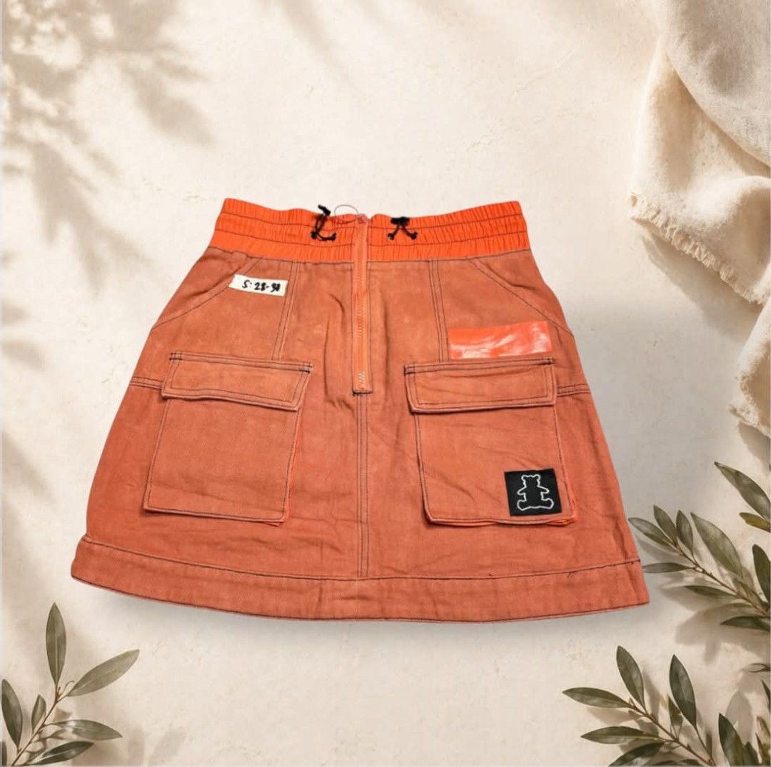 Bobby Abley Orange Cargo Denim Skirt with Bear Patch (Category: Skirts) located in Danao, Cebu. Submitted by traya07 (Listing ID 1469707541, Image 2). Description: - Brand: Bobby Abley - Style: Orange denim cargo skirt - Fit: Elasticated waist with zipper closure and black drawstring - Pockets: Large utility pockets on the front and back - Details: Contrast black stitching, fun bear graphic patch, and logo embroidery - Vibe: Distinctive streetwea