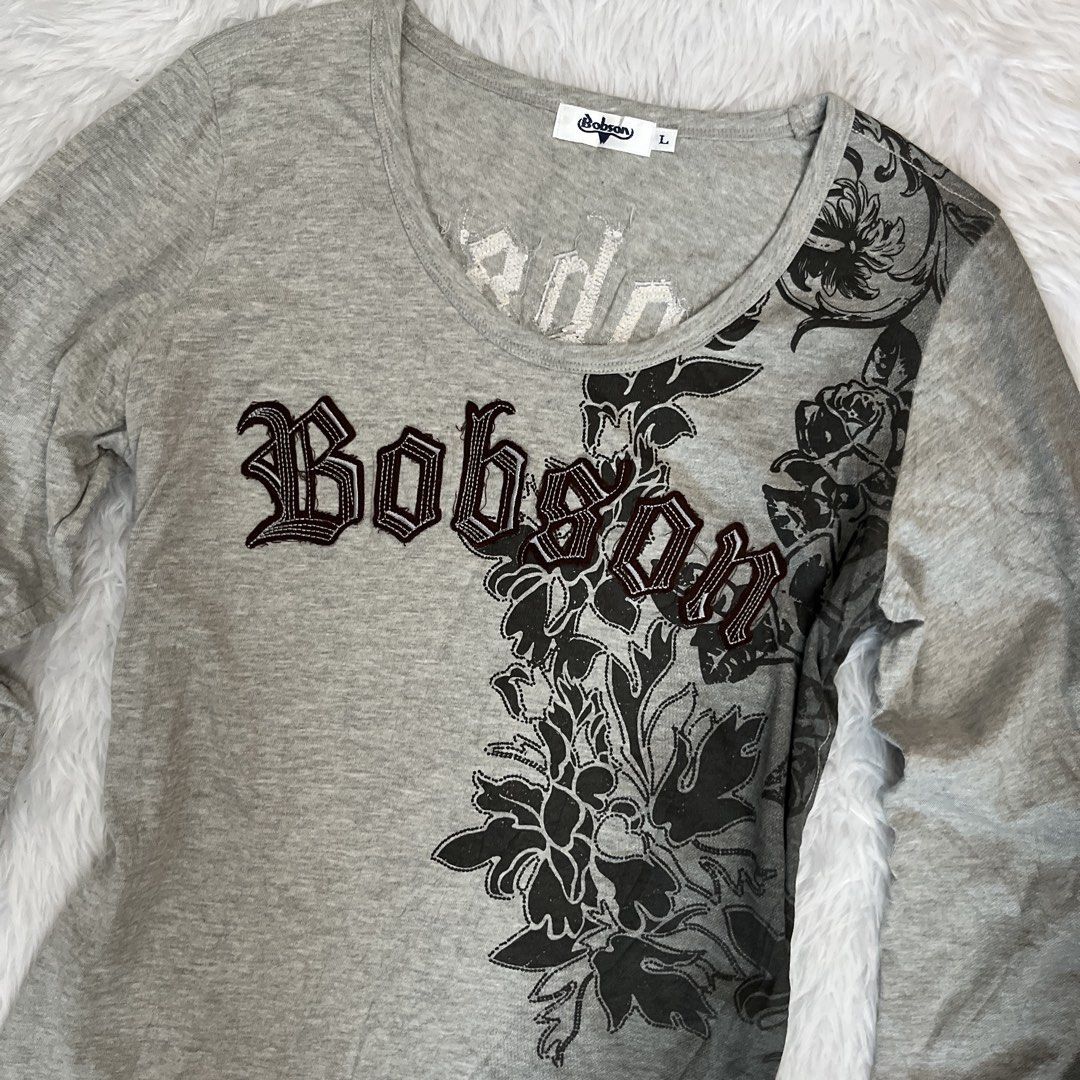 Bobson Grey Graphic Long Sleeve Top (Category: Longsleeves) located in Maasin. Submitted by taraa18 (Listing ID 1469583803, Image 2). Description: - Brand/Model: Bobson long sleeve top - Color: Grey - Size: Tag size L - Neckline: Scoop neckline - Design: Dark floral print graphics down one side and back - Detailing: Embroidered gothic lettering across chest and upper back.