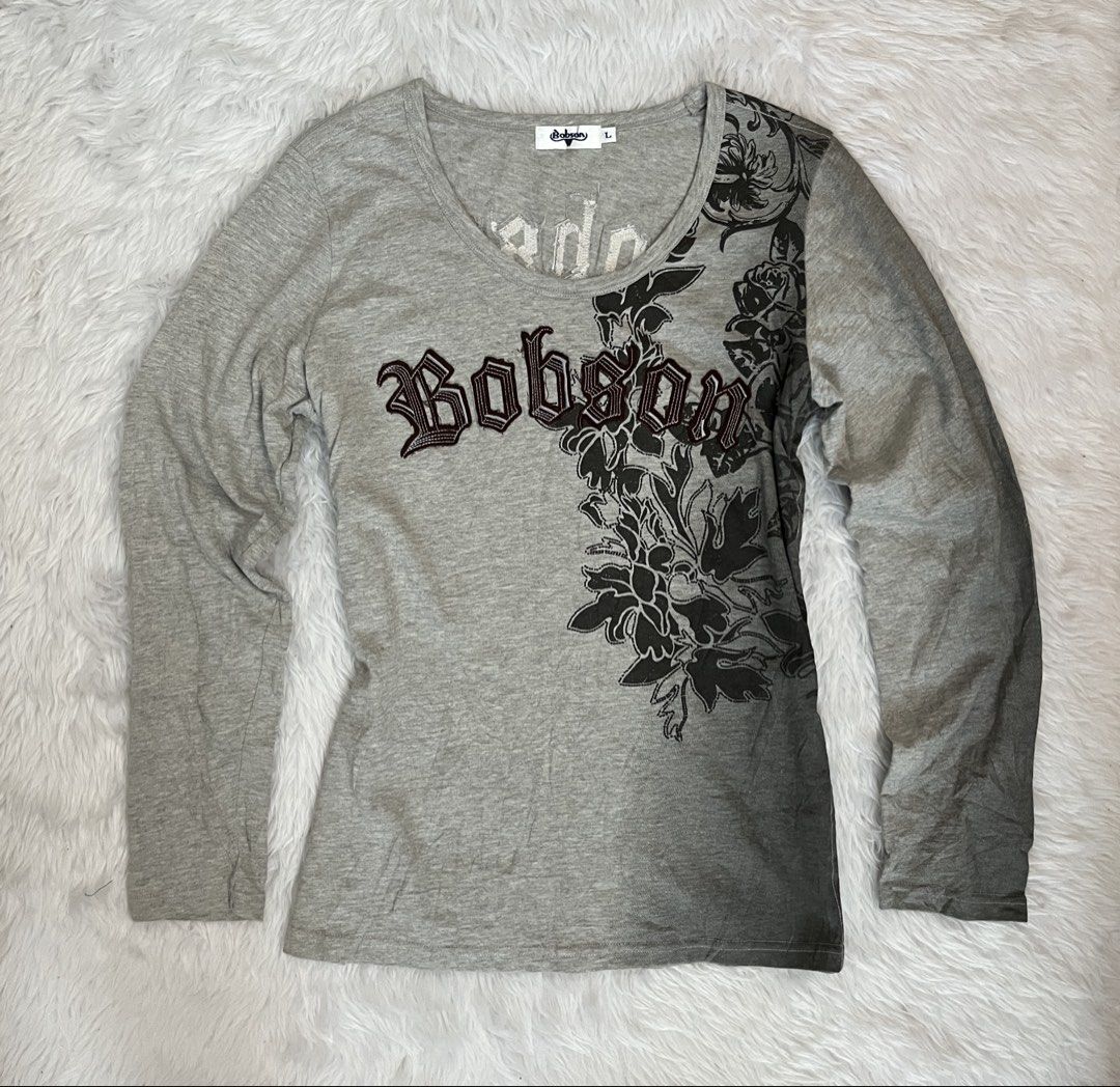 Bobson Grey Graphic Long Sleeve Top (Category: Longsleeves) located in Maasin. Submitted by taraa18 (Listing ID 1469583803, Image 1). Description: - Brand/Model: Bobson long sleeve top - Color: Grey - Size: Tag size L - Neckline: Scoop neckline - Design: Dark floral print graphics down one side and back - Detailing: Embroidered gothic lettering across chest and upper back.