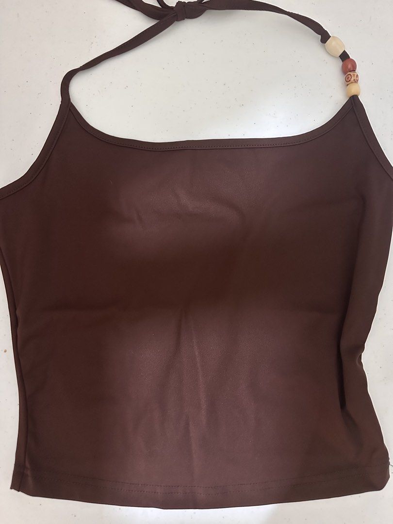 Brown Halter Tank Top with Beaded Straps (Category: Sleeveless) located in Pasig City. Submitted by prelovedbysco (Listing ID 1469694126, Image 1). Description: - Color: Rich brown - Design: Halter tank top with a straight neckline - Detail: Unique beaded threading on one strap - Support: Built-in shelf bra lining - Material: Soft stretch fabric - Styling: Great to pair with high-waisted jeans or skirts Perfect for beach trips.