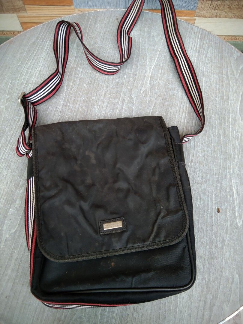 Burberry black nylon messenger bag with striped strap (Category: Sling Bags) located in Manila. Submitted by mysticshark-0a05e9 (Listing ID 1469754715, Image 1). Description: - Brand: Burberry - Material: Durable black nylon - Strap: Long adjustable strap with red, white, and black iconic stripes - Closure: Flap front with metal logo plaque - Interior: Includes zipper pocket and leather brand tag - Condition: Inside fabric shows general wear and 