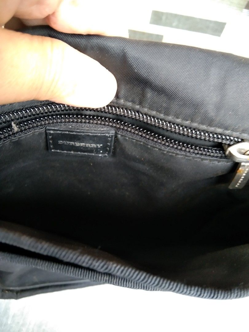 Burberry black nylon messenger bag with striped strap (Category: Sling Bags) located in Manila. Submitted by mysticshark-0a05e9 (Listing ID 1469754715, Image 2). Description: - Brand: Burberry - Material: Durable black nylon - Strap: Long adjustable strap with red, white, and black iconic stripes - Closure: Flap front with metal logo plaque - Interior: Includes zipper pocket and leather brand tag - Condition: Inside fabric shows general wear and 