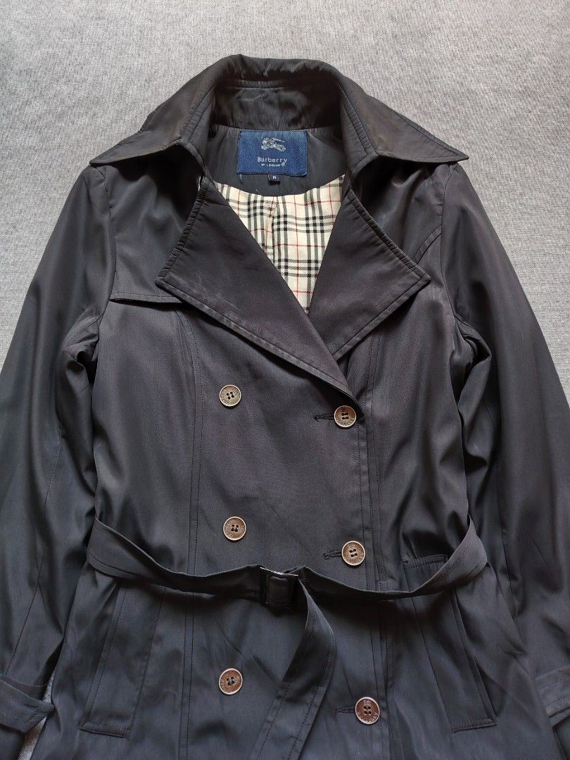 Burberry Double Brested Trench Coat (Category: Coats, Jackets and Outerwear) located in Taguig. Submitted by _theroom.ph (Listing ID 1469636775, Image 2). Description: Burberry London trench coat in black, size M. Double-breasted front with branded buttons. Matching waist belt and adjustable sleeve straps. Classic check lining inside. Main fabric 83% cotton, 15% nylon, 2% elastane. 100% cupro lining. Made in Hong Kong. Dry clean only, remember to