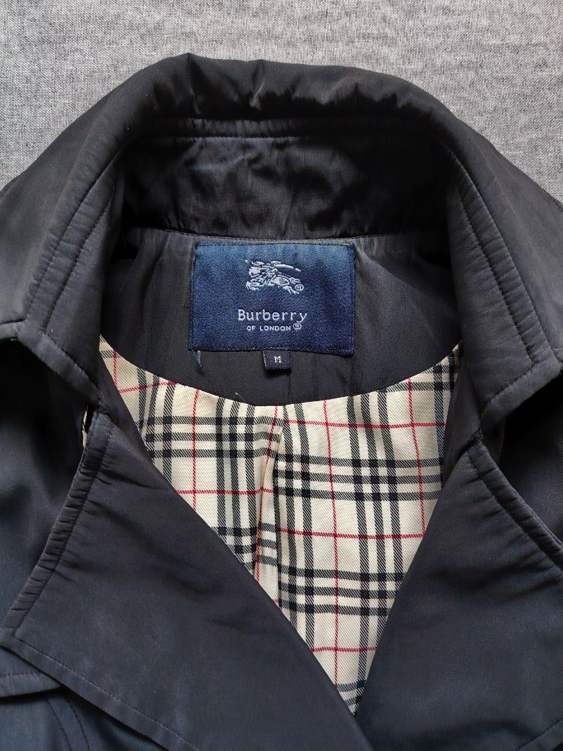 Burberry Double Brested Trench Coat (Category: Coats, Jackets and Outerwear) located in Taguig. Submitted by _theroom.ph (Listing ID 1469636775, Image 3). Description: Burberry London trench coat in black, size M. Double-breasted front with branded buttons. Matching waist belt and adjustable sleeve straps. Classic check lining inside. Main fabric 83% cotton, 15% nylon, 2% elastane. 100% cupro lining. Made in Hong Kong. Dry clean only, remember to