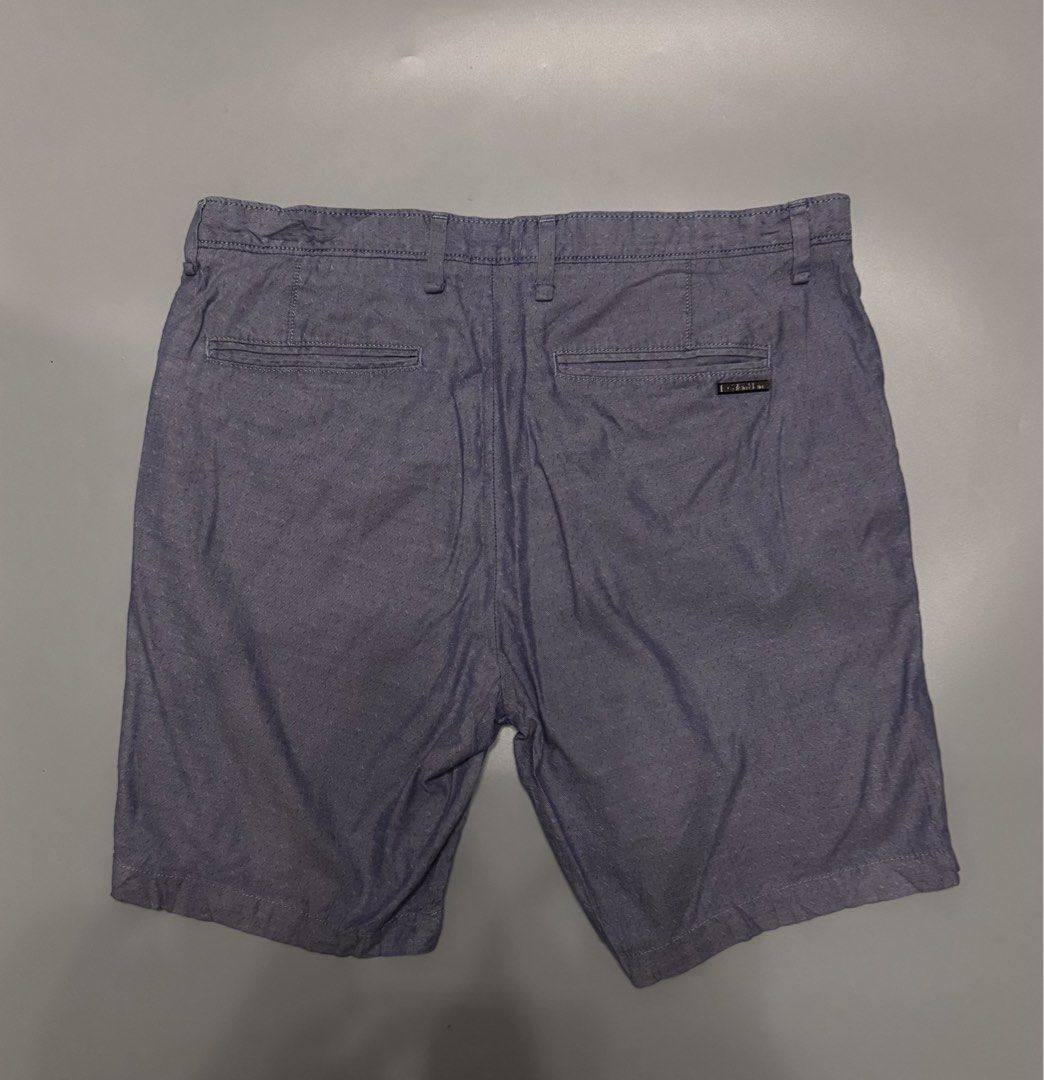 Calvin Klein Grey Blue Shorts Size 32 (Category: Shorts) located in Alaminos. Submitted by outfitcheck.ph (Listing ID 1469698072, Image 2). Description: - Brand: Calvin Klein - Size: Men's 32 - Color: Blue-Grey - Closure: Standard button and zip with belt loops - Pockets: Two front pockets and two back welt pockets - Details: Subtle metal logo badge on the right back pocket - Condition: Clean inside lining with printed brand label.