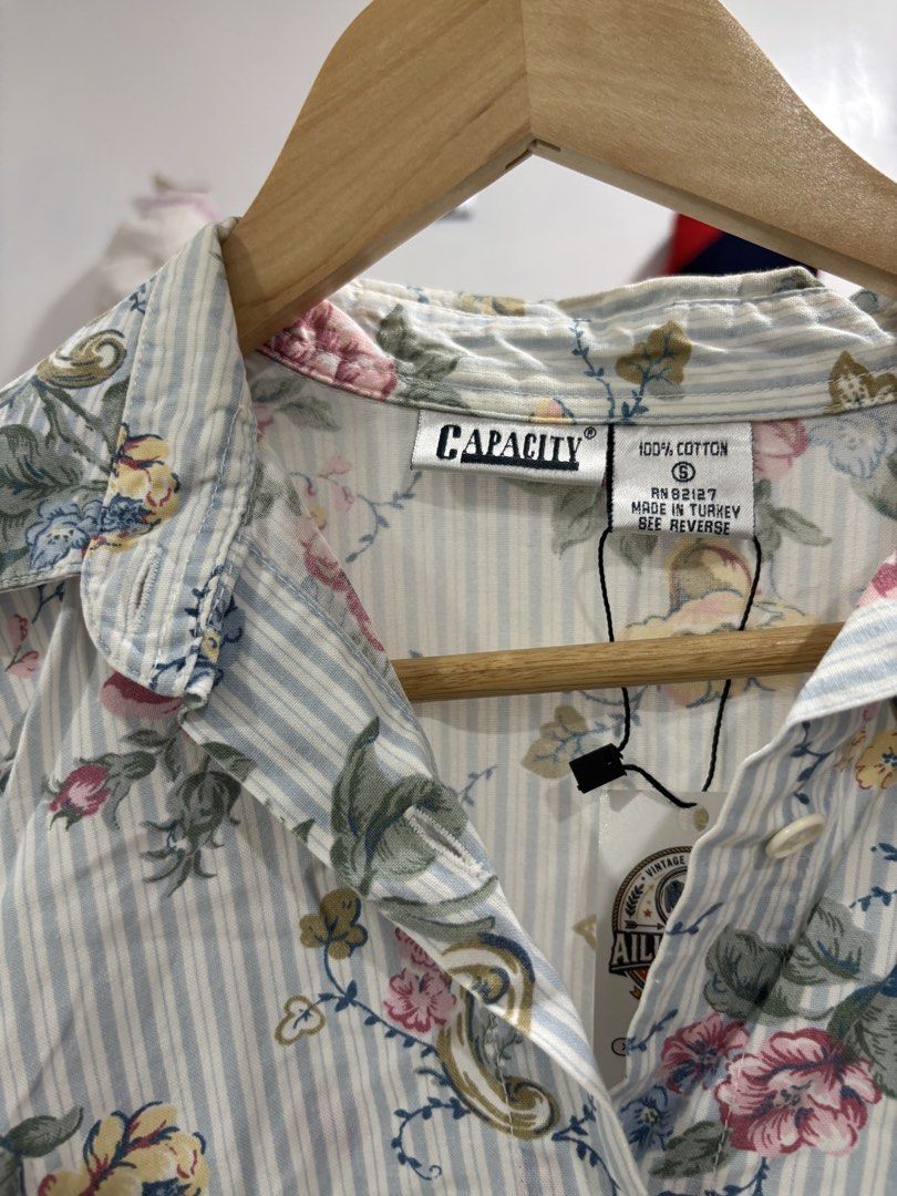 Capacity Floral Striped Short Sleeve Shirt (Category: Shirts) located in Calbayog City. Submitted by zaxcheus_castillo1708 (Listing ID 1469669778, Image 2). Description: - Brand: Capacity - Size: Small (Tag still attached) - Material: 100% Cotton, Made in Turkey - Design: Short sleeves, pointed collar, button-down front - Pattern: Light blue vertical stripes with all-over pink and yellow floral print - Condition: Brand new with tags.