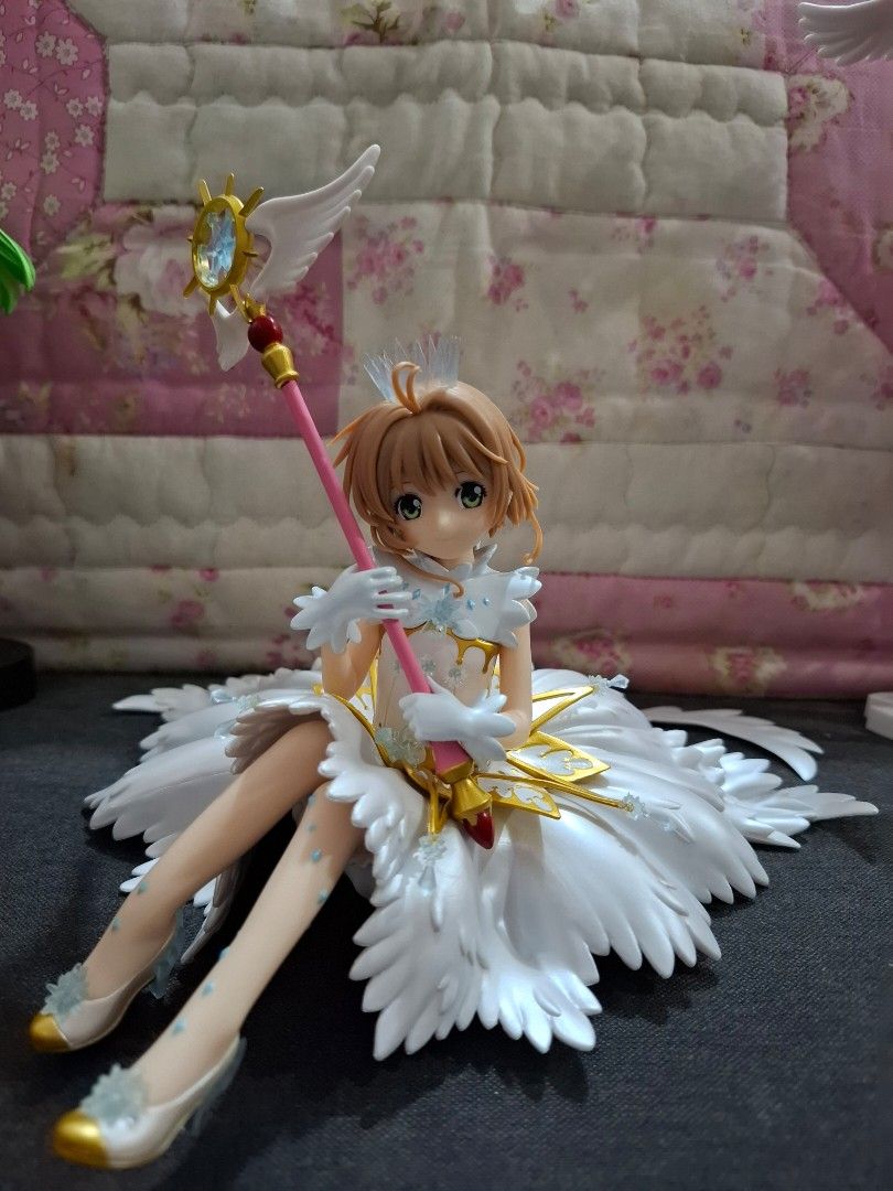 Cardcaptor Sakura Kinomoto Clear Card Version Figure (Category: Figurines & Statues) located in Orion. Submitted by timburtonfan (Listing ID 1469575290, Image 1). Description: - Character: Cardcaptor Sakura - Outfit: White feathered dress with white gloves and matching shoes - Accessories: Holding the pink star wand with gold details - Features: Large detailed wings and blue crystal accents - Height: Approx 15cm tall - Condition: Brand new / Mint