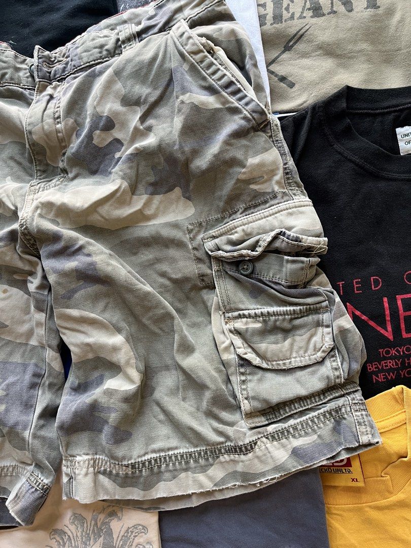 Cargo Supply Camouflage Cargo Shorts (Category: Shorts) located in Baao. Submitted by plainclothesdept (Listing ID 1469696906, Image 3). Description: cargo supply camo cargo shorts waist - 34 in. length - 21 in. hem - 12 in. paint stains, signs of wear - Brand: Cargo Supply - Design: Grey and white camo pattern with a cool red inner waistband detail - Closure: Classic button fly - Storage: Multiple side cargo pockets plus standard front and back 