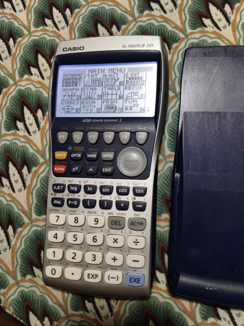 Casio fx-9860GII SD Graphing Calculator (Category: Office & Business Technology) located in Lubao. Submitted by aczcollectibles (Listing ID 1469616888, Image 3). Description: Casio fx-9860GII SD graphing calculator in working condition. Screen turns on and displays the main menu clearly. Buttons are all intact with legible text markings. Includes the hard protective slide cover. Standard scientific and graphing functions available. Battery compar