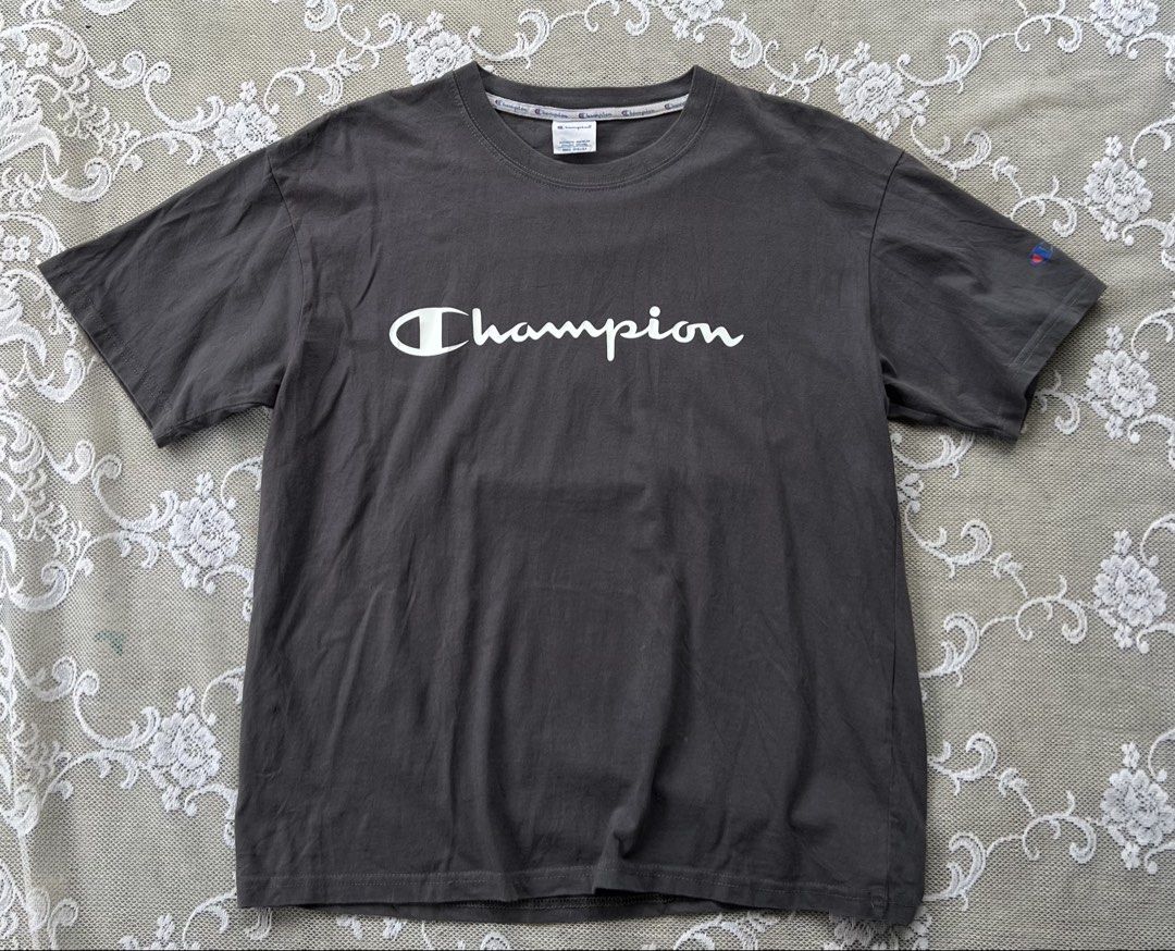 Champion Dark Grey T-shirt with Big Logo (Category: Tshirts & Polo Shirts ) located in Manila. Submitted by trustedmichael. (Listing ID 1469710021, Image 2). Description: Champion W 21 L 26 M on tag - Brand: Champion - Color: Dark grey with a vintage washed look - Design: Script logo across the chest and large faded C logo on the back - Details: Crew neck, short sleeves, embroidered C logo patch on left sleeve cuff, and branded inside collar tapi