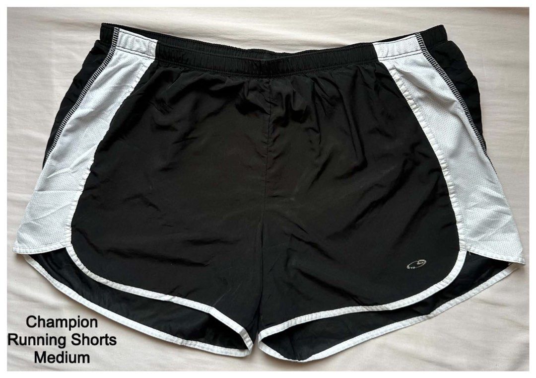 Champion Running Shorts Medium (Category: Activewear) located in Cebu City. Submitted by purgemycloset (Listing ID 1469650131, Image 1). Description: - Brand: Champion - Color: Black with white side panels and piping - Size: Medium (fits true to size) - Material: Lightweight athletic fabric - Features: Comfortable elastic waistband - Condition: Good, with minor wear on the printed leg logo (see close-up photo) - Perfect for workouts, running, or 