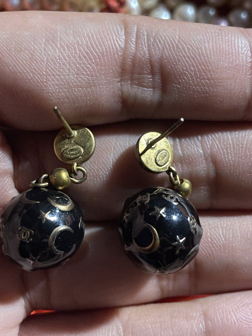 Chanel Earrings (Category: Luxury Accessories) located in Dumaguete. Submitted by jaymharr (Listing ID 1469694331, Image 2). Description: Chanel Star and Moon Resin Sphere Drop Earrings. This celestial-themed vintage costume jewelry design features black round studs detailed with the signature interlocking gold CC logo. Suspended below are large black resin orbs adorned with gold inlaid crescent moons, stars, and tiny dotted constellations..
